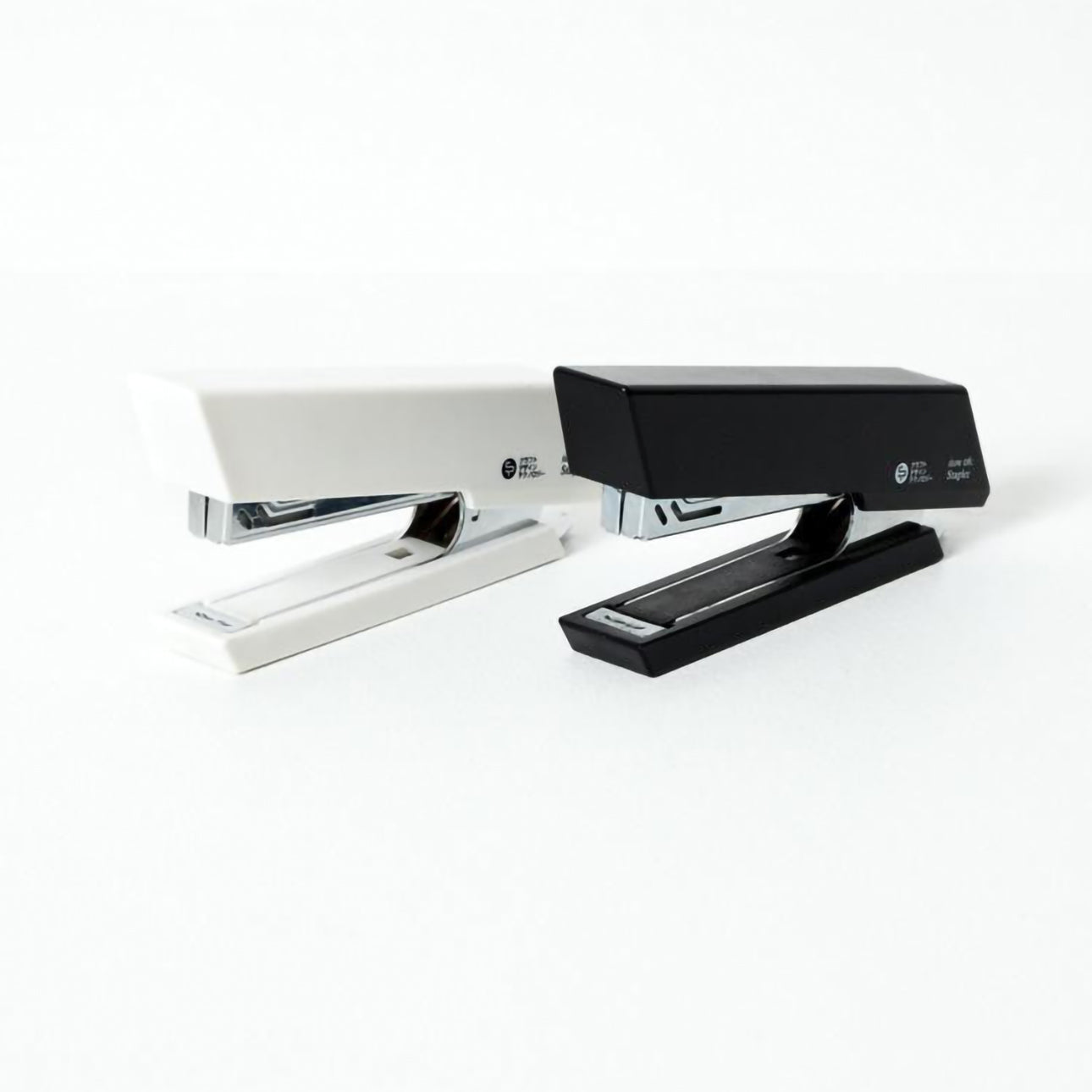 Agrafeuses Yugen lab au design angulaire minimaliste, disponibles en blanc et noir, en plastique robuste.