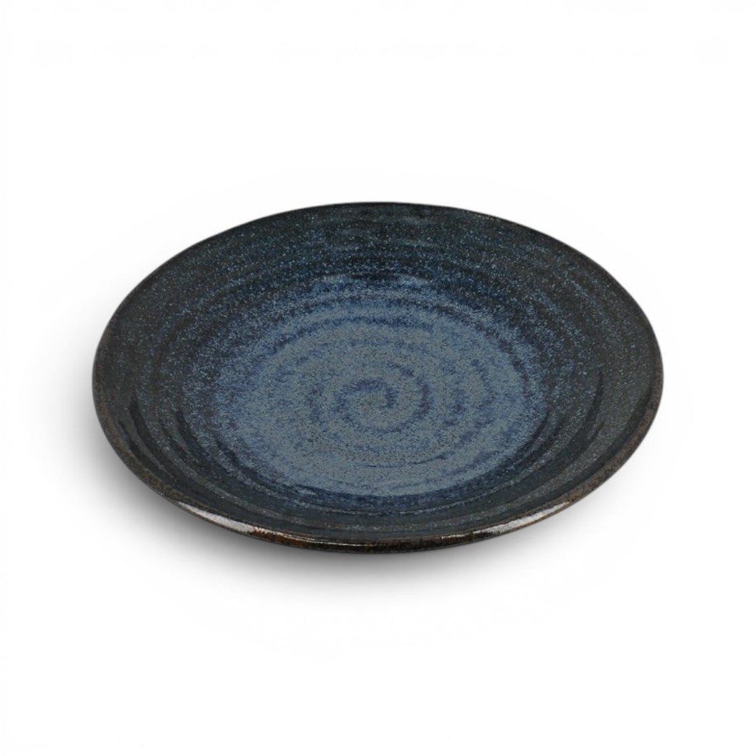 Grande assiette en céramique Yugen lab bleu nuit avec un motif en spirale inspiré de l'esthétique zen japonaise.