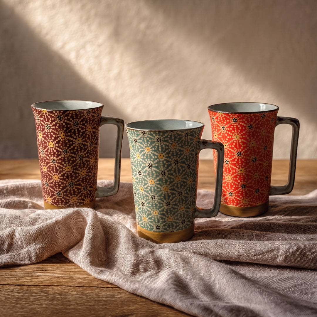 Trois mugs Yugen lab Hanasibori hauts et évasés avec motifs floraux japonais, détails dorés et anses angulaires.