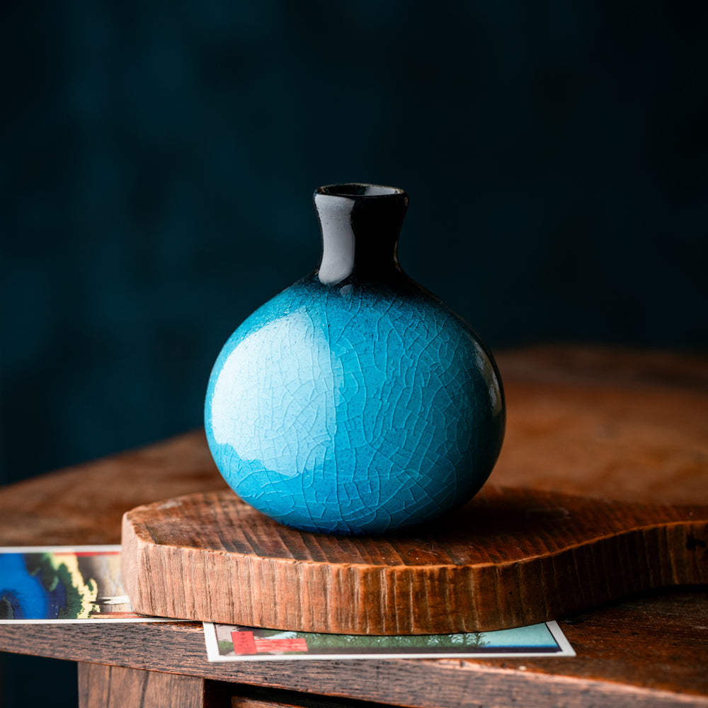 Petit vase japonais turquoise en céramique craquelée sur table en bois