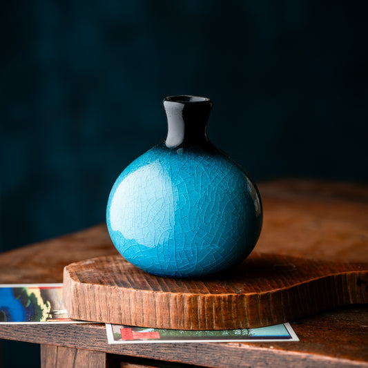Petit vase japonais turquoise en céramique craquelée sur table en bois