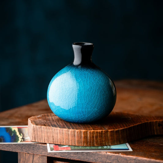 Petit vase japonais turquoise en céramique craquelée sur table en bois