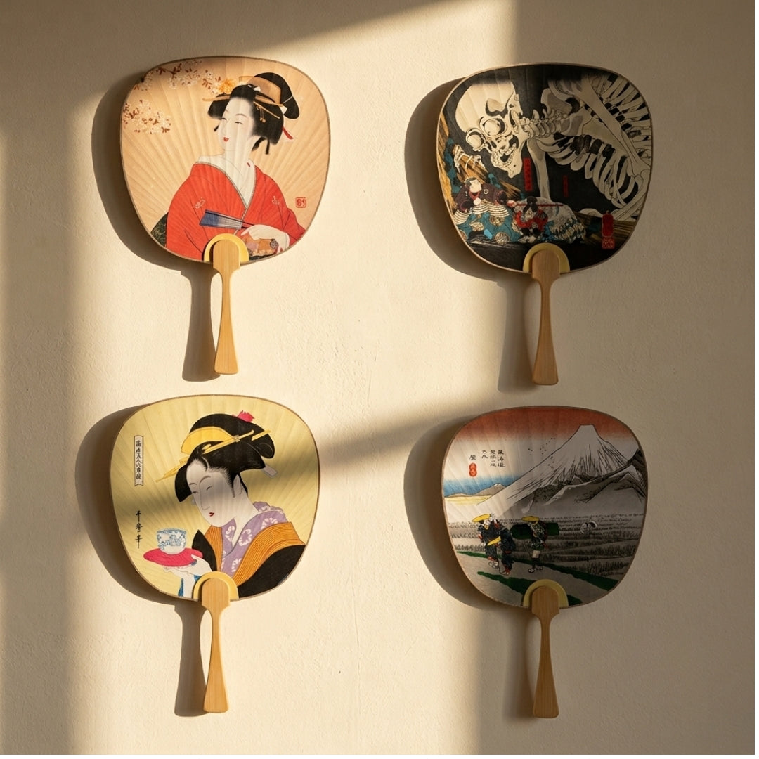Éventails japonais en papier et bambou avec quatre motifs traditionnels, présentés devant un fond crème.