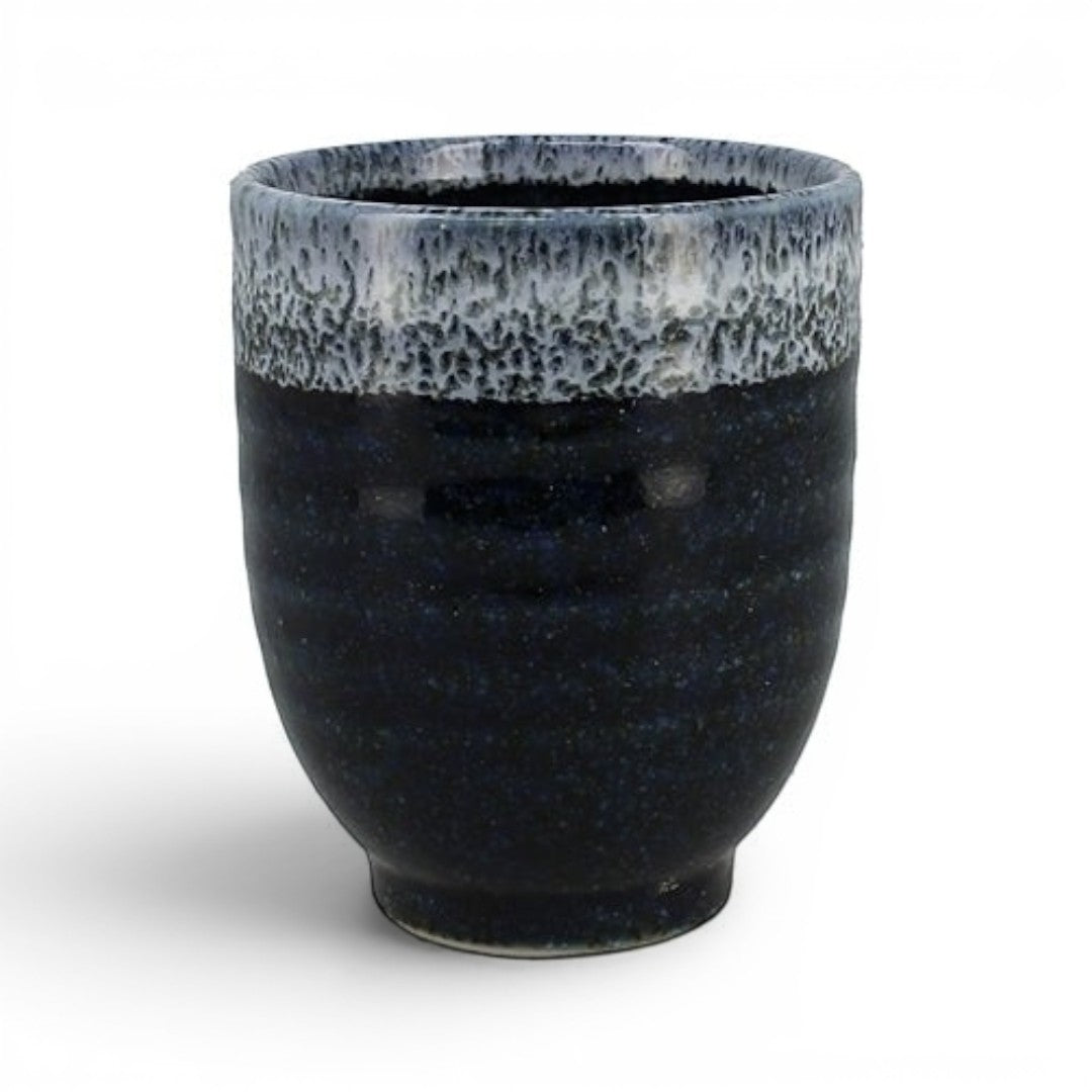 Vue de face d'une tasse à thé en porcelaine bleu marine avec rebord bleu clair texturé sur fond blanc.