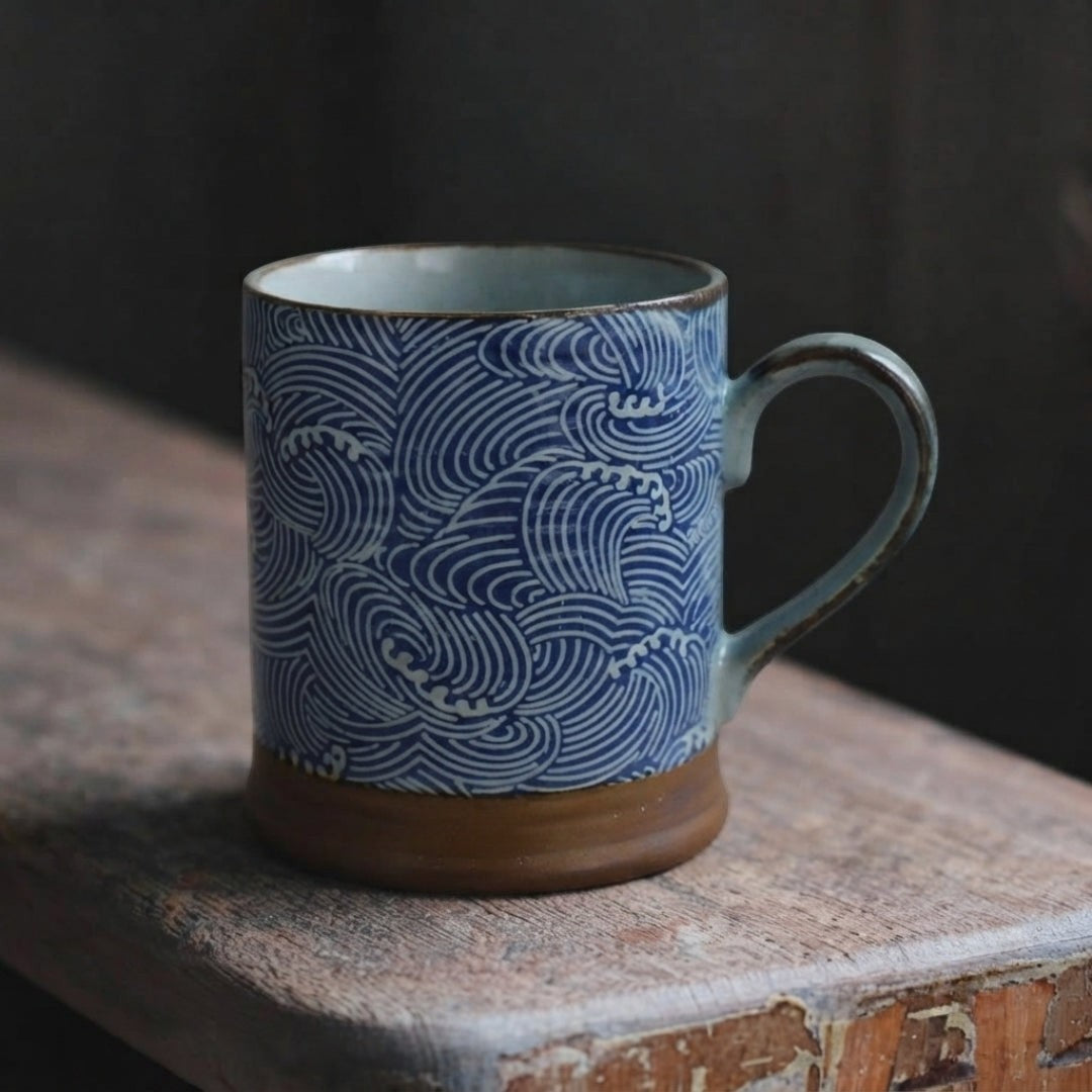 Mug japonais en porcelaine à motif de vagues bleues avec anse sur une table en bois.