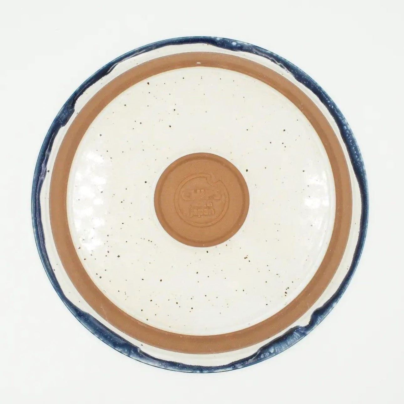 Assiette Yugen lab en céramique japonaise avec contour bleu et fond blanc moucheté, vue de dessous.