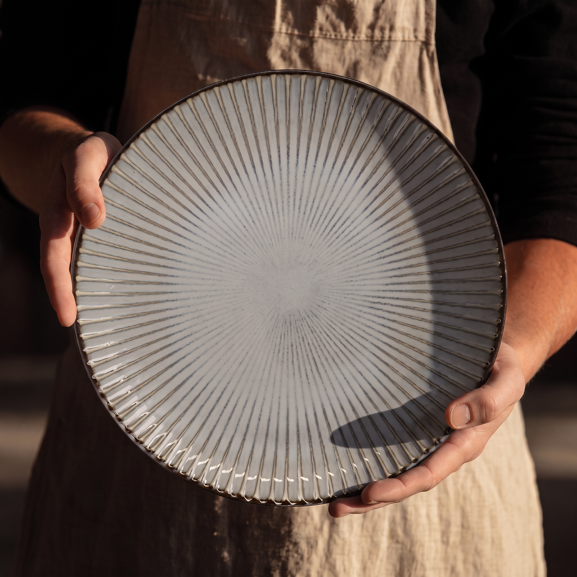 Assiette Yugen lab en céramique blanche de 24 cm avec fines rayures gris-brun rayonnantes et bordure sombre contrastée