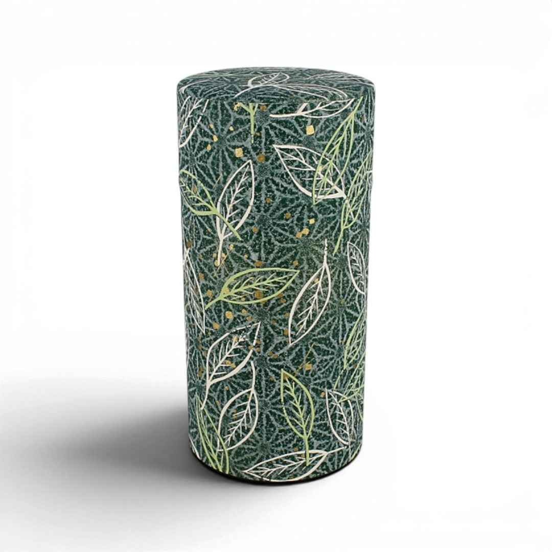 Boîte à thé japonaise Yugen lab cylindrique en fer blanc et papier washi avec motif de feuilles vertes et dorées.