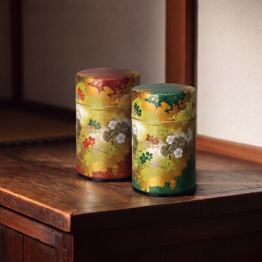 Deux boîtes à thé Yugen lab en fer blanc, cylindriques, décorées de motifs floraux japonais dorés, rouges et verts.