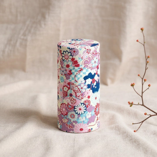 Boîte à thé japonaise Yugen lab cylindrique avec motif floral violet et géométrique sur fond beige texturé