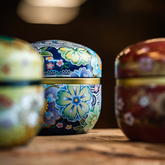 Boîte à thé japonaise Yugen lab avec motifs floraux colorés sur fond bleu, idéale pour conserver le thé en vrac.