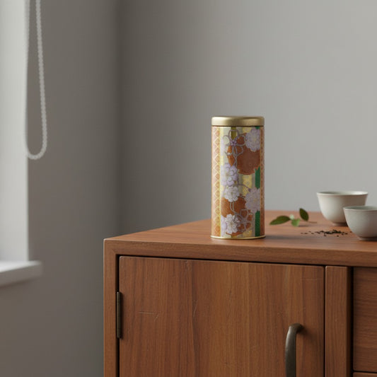 Boîte à thé japonaise Yugen lab en métal orange avec motifs floraux délicats posée sur un meuble en bois