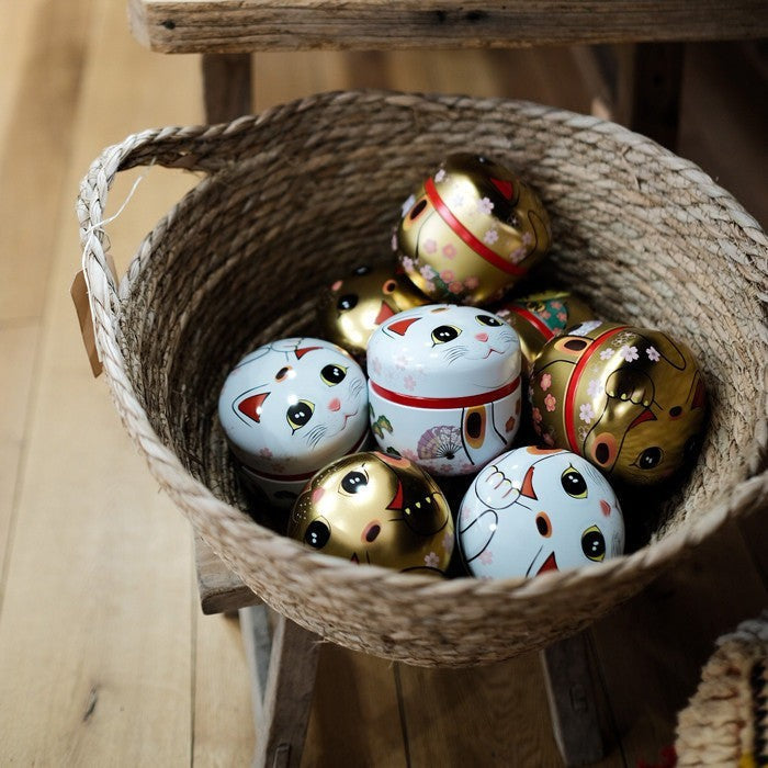 Boîtes à thé Yugen lab en fer blanc motif chat Maneki Neko doré et blanc dans un panier en osier
