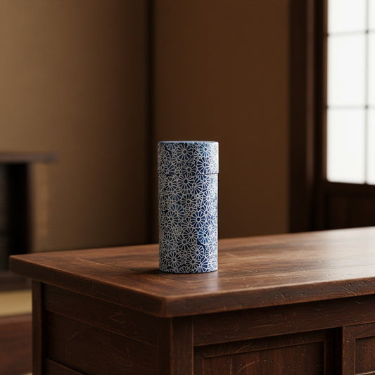 Boîte à thé Yugen lab cylindrique en papier washi bleu à motif floral traditionnel posée sur une table en bois