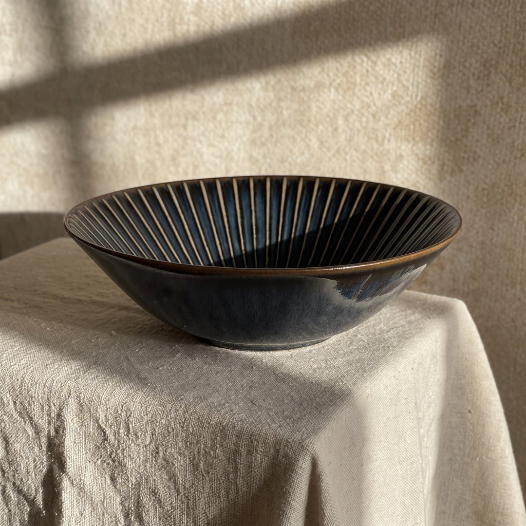 Bol japonais Yugen lab en céramique bleue évasée avec des lignes verticales graphiques sur une nappe en lin