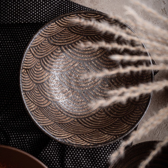 Bol japonais Yugen lab en porcelaine brune avec motif vagues gravé, vue de dessus sur fond textile sombre.