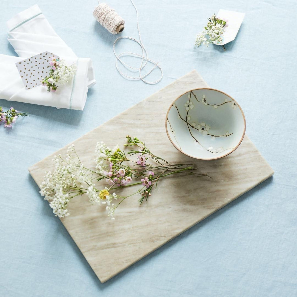 Bol japonais en céramique Yugen lab bleu clair avec motifs de fleurs blanches et lianes sur une planche en marbre