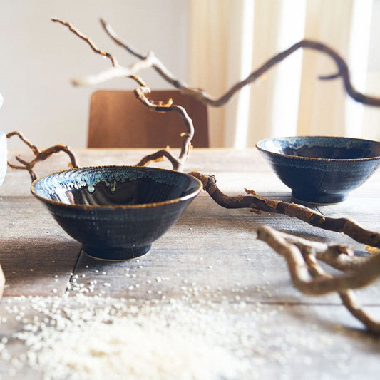 Bol japonais Yugen lab en porcelaine bleu océan avec détails blancs et verts sur une table en bois rustique