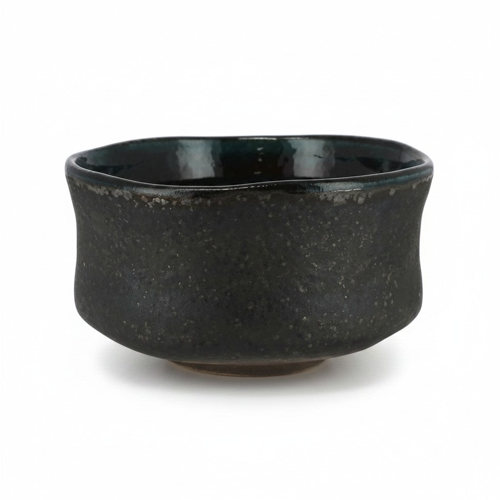 Bol matcha Yugen lab en céramique noire texturée avec intérieur émaillé vert profond, style wabi-sabi japonais.
