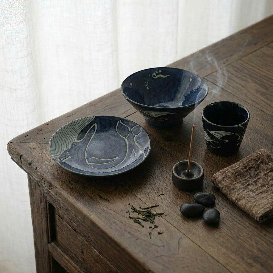 Ensemble de vaisselle Yugen lab en porcelaine bleu profond avec motifs de baleines sur une table en bois rustique