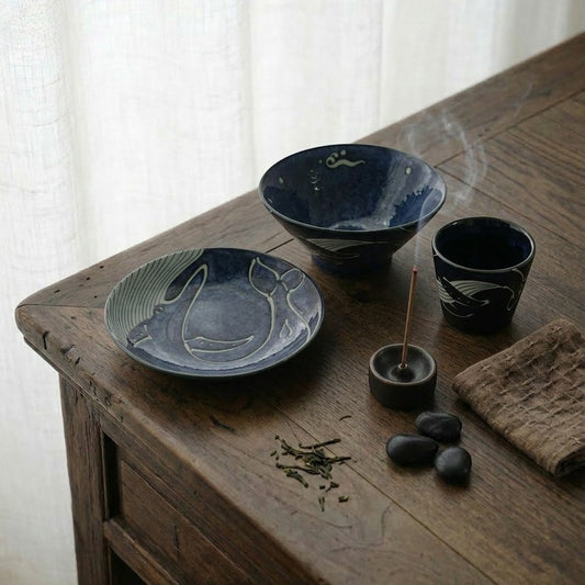 Ensemble de vaisselle Yugen lab en porcelaine bleu profond avec motifs de baleines sur une table en bois rustique