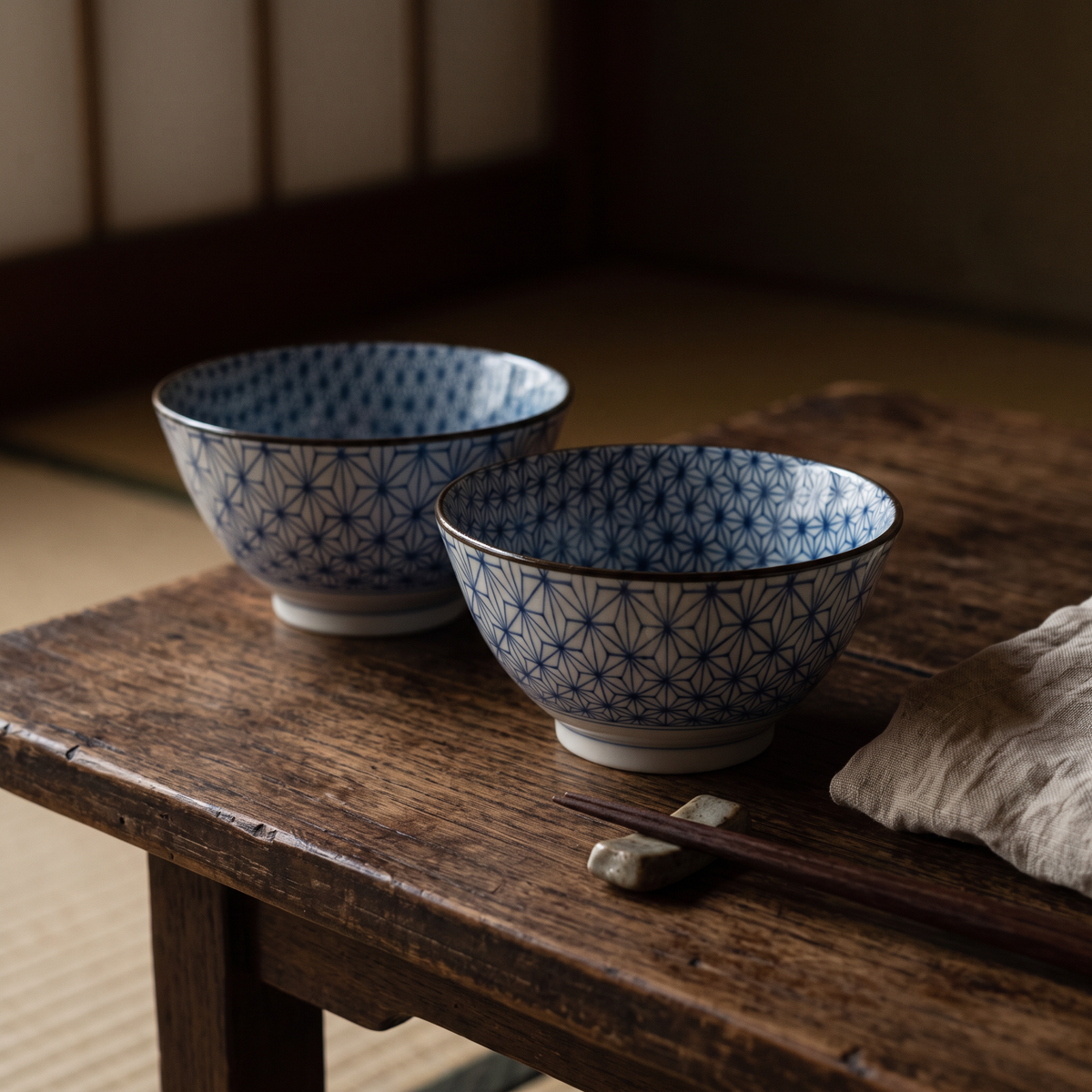 Two Japanese ramen bowls with blue Asanoha pattern on a wooden table, with chopsticks