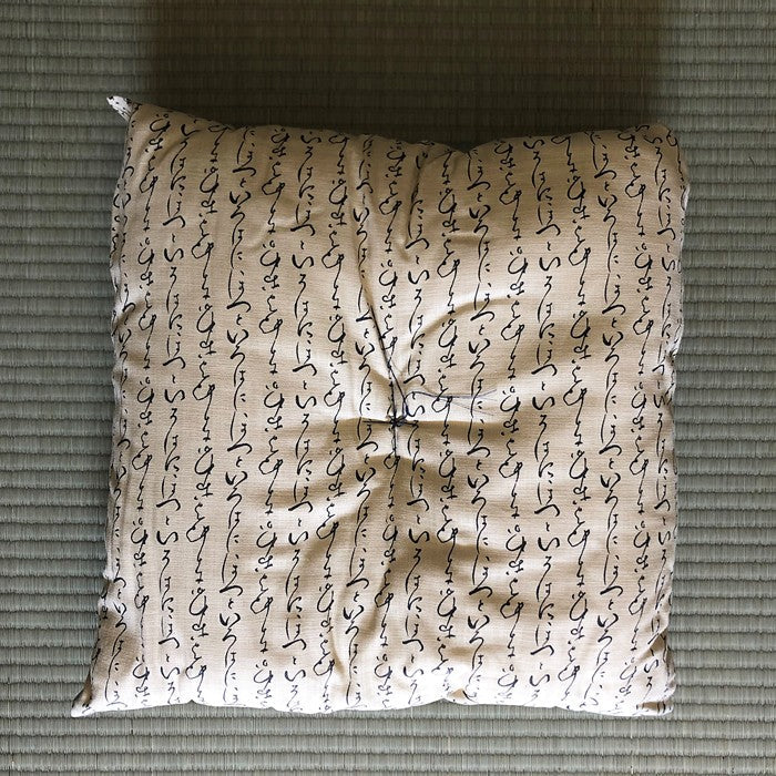 Coussin Yugen lab en coton beige avec calligraphie japonaise noire, posé sur un tatami traditionnel.
