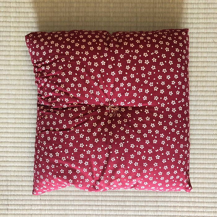 Coussin Yugen lab en coton rouge à motifs de petites fleurs blanches style japonais posé sur un tatami