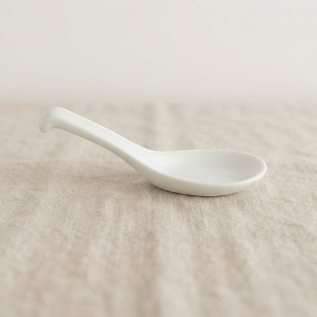 Cuillère Classic Yugen lab en porcelaine blanche émaillée au design minimaliste et épuré sur fond en lin beige