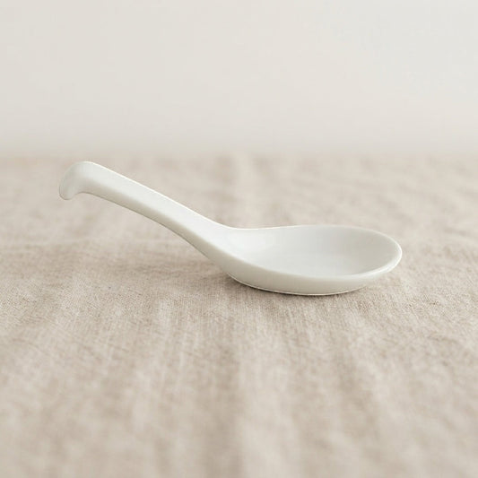 Cuillère Classic Yugen lab en porcelaine blanche émaillée au design minimaliste et épuré sur fond en lin beige