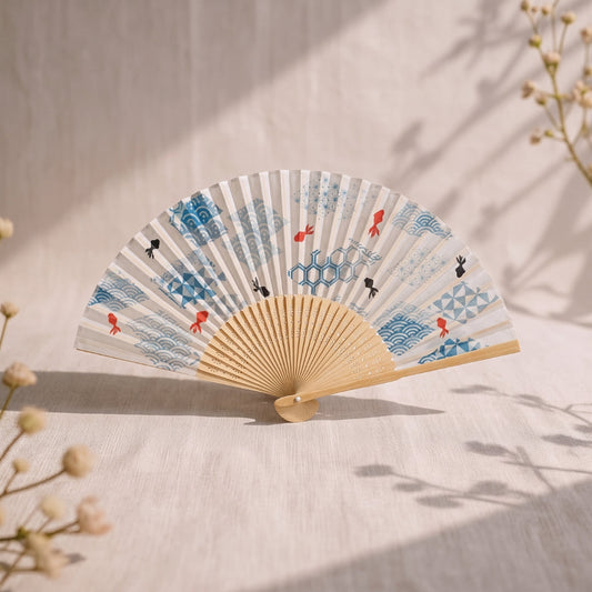Éventail japonais Yugen lab en bambou et polyester avec motifs de poissons rouges et vagues bleues sur fond écru.