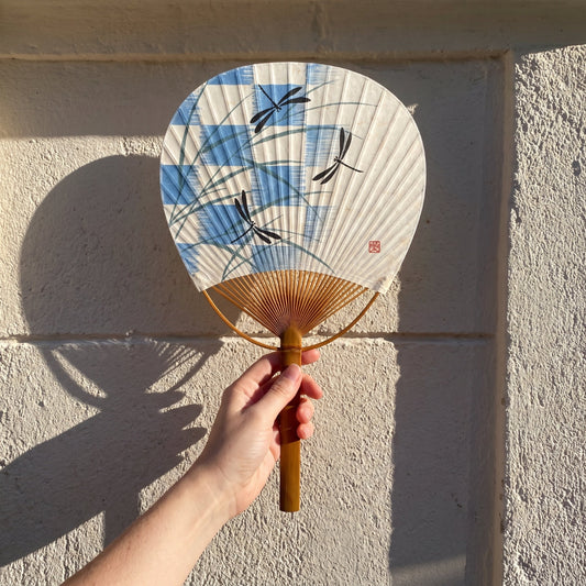 Éventail japonais Uchiwa Yugen lab en papier et bambou, décoré de libellules noires et d'herbes bleu-gris sur fond écru.