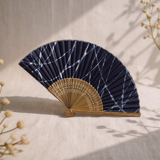 Éventail Yugen lab en tissu bleu marine et beige avec motifs marbrés, monté sur une structure en bois sculpté.