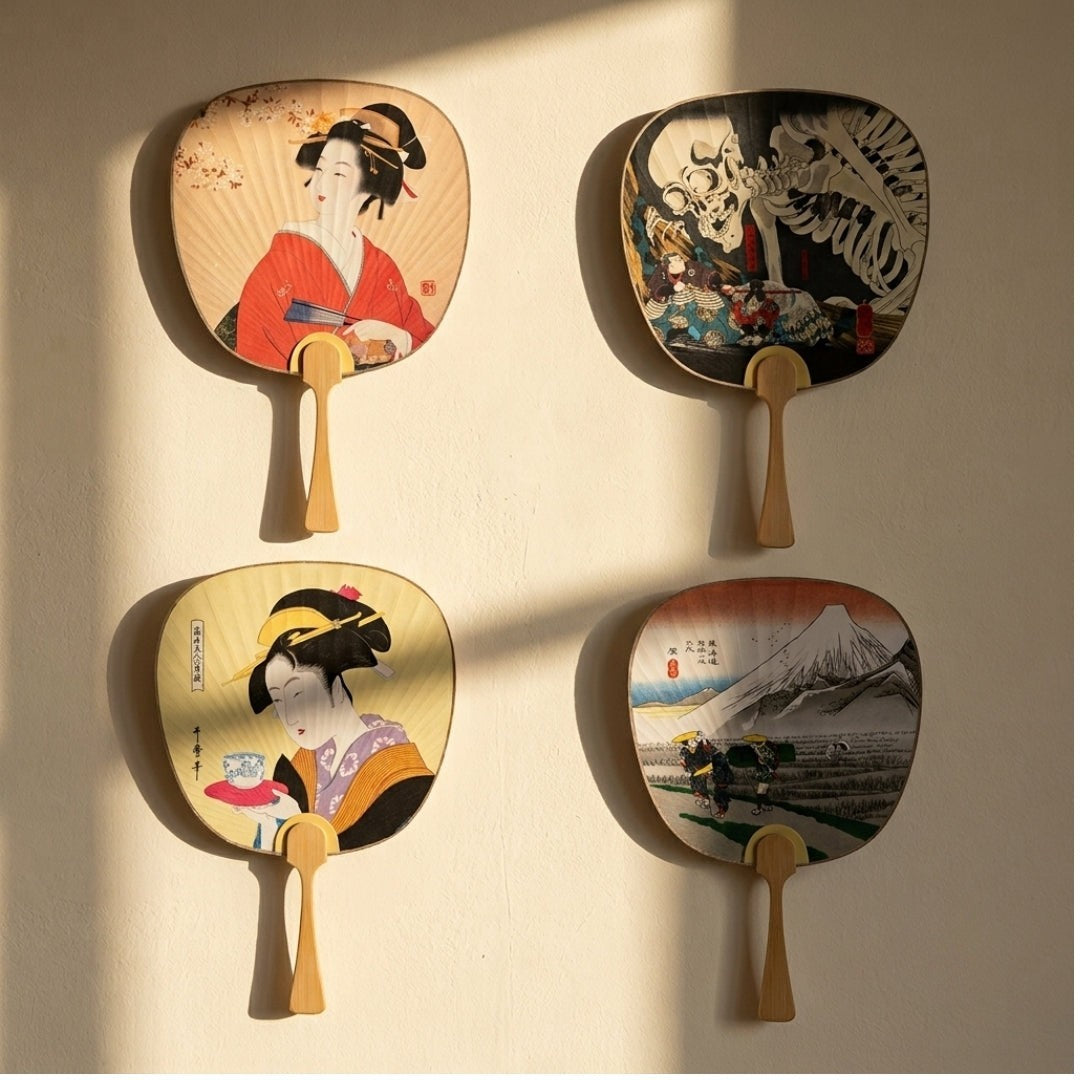 Quatre éventails Yugen lab en papier et bambou avec motifs traditionnels japonais exposés sur un mur clair.