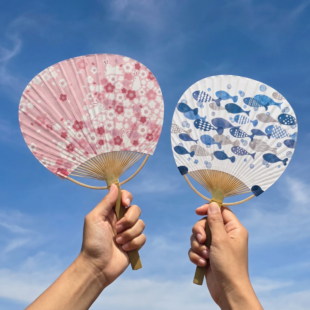 Yugen lab éventails ronds uchiwa en bambou, un motif rose avec lapins et un motif bleu avec poissons sur ciel bleu.