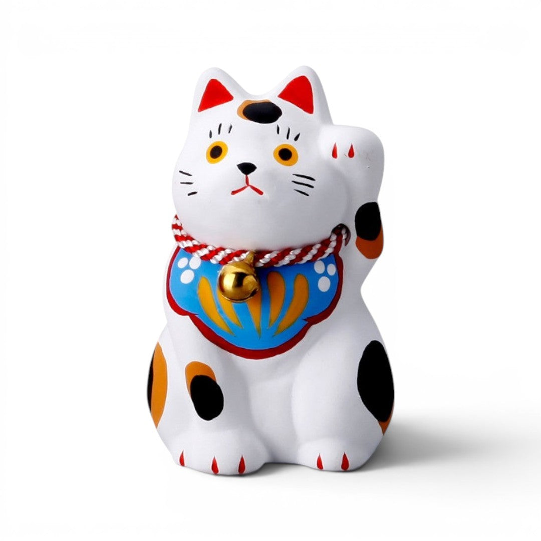 Figurine Maneki Neko Yugen lab en céramique blanche avec taches colorées, grelot doré et patte levée porte-bonheur.