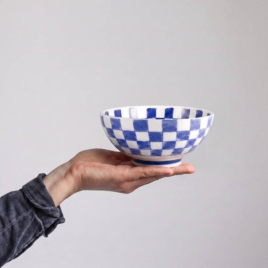 Grand bol japonais en porcelaine Yugen lab avec motif damier bleu et blanc tenu dans une main