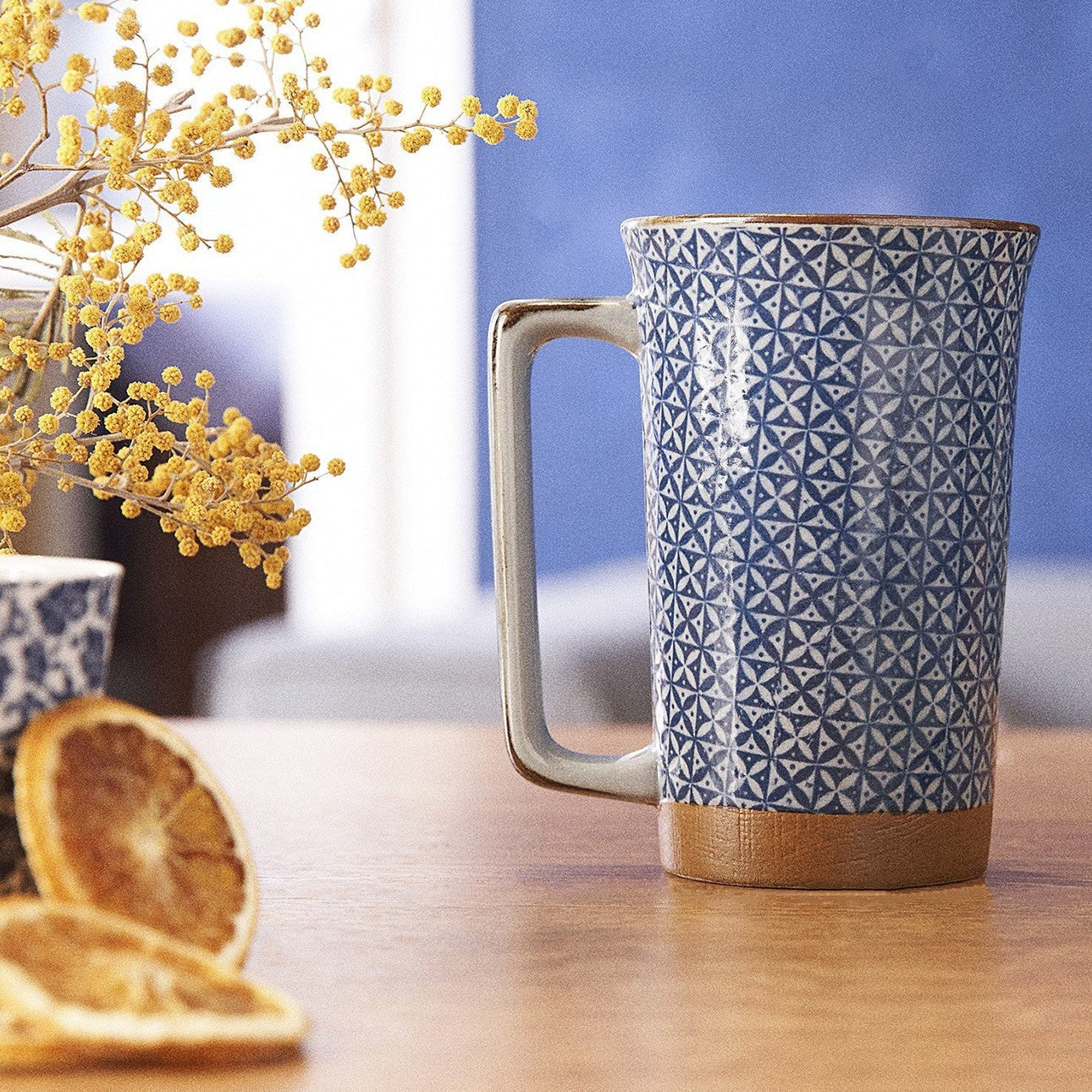 Grand mug japonais Yugen lab en céramique bleue et blanche avec motif diamant et base couleur terre sur une table