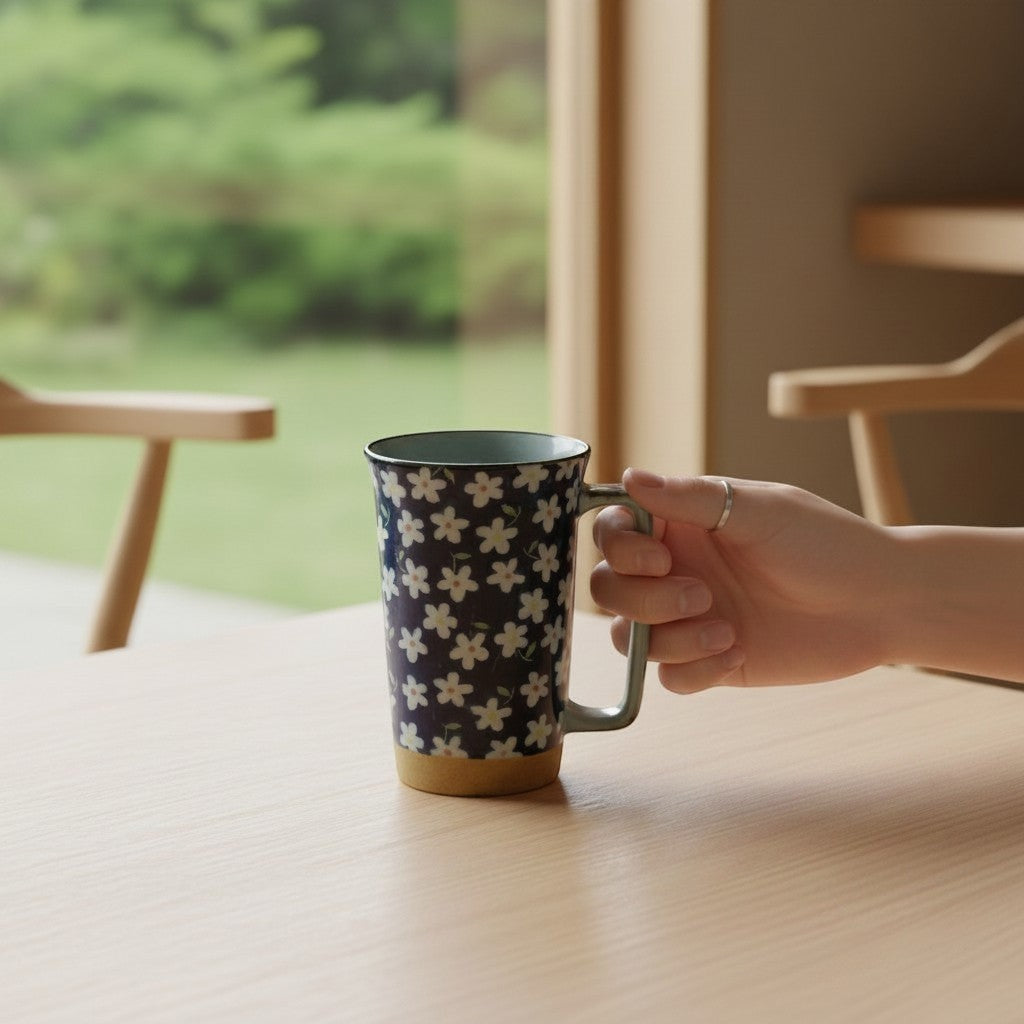 Mug en céramique Yugen lab bleu avec motif floral blanc Kobana et anse rectangulaire sur une table en bois