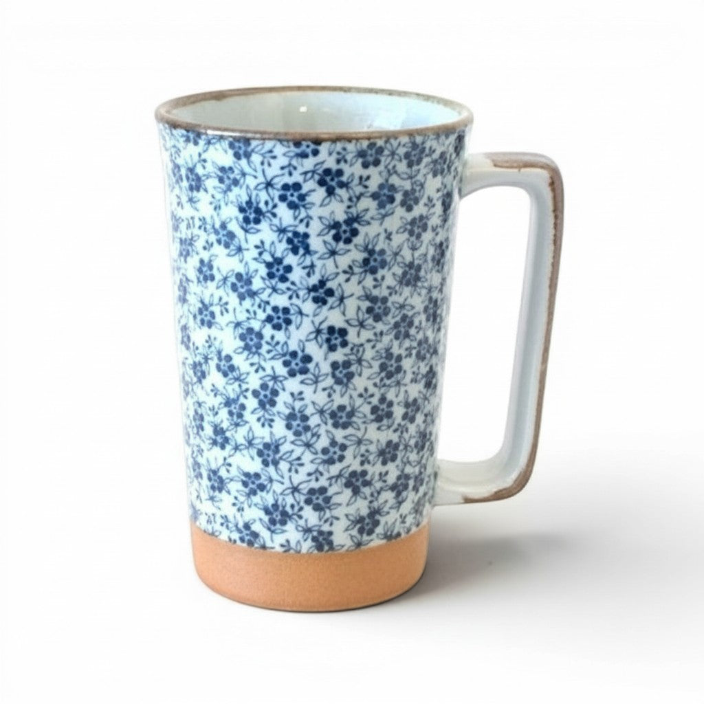 Grand mug Yugen lab en céramique blanche et bleue avec motif floral délicat et base en terre cuite naturelle.
