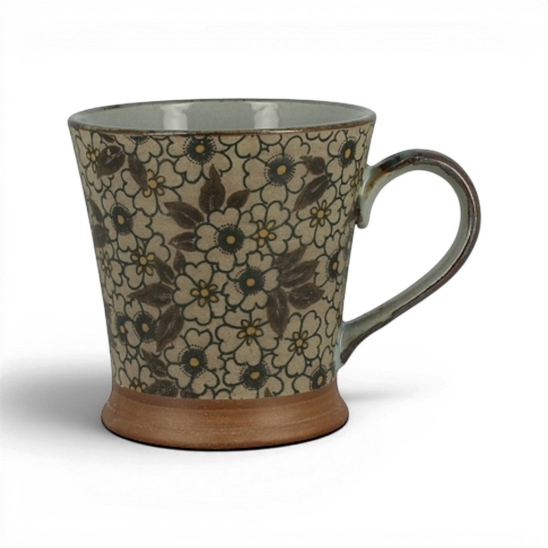 Mug Yugen lab en céramique émaillée à motif floral rétro, fleurs ivoire et feuilles brunes sur base naturelle.