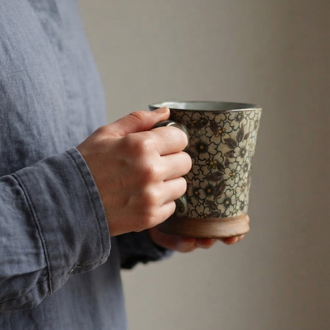 Mug Yugen lab en céramique émaillée à motif floral rétro, tenu en main, base en terre naturelle, style japonais.
