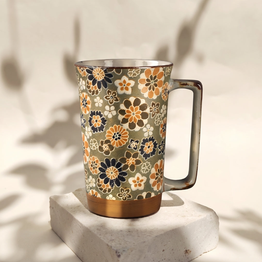 Grand mug Yugen lab en céramique japonaise à motifs floraux crème, ocre et bleu sur fond vert clair avec large anse.