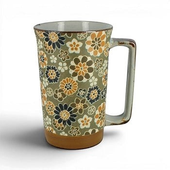 Grand mug Yugen lab en céramique japonaise avec motifs floraux ocre, bleu et crème sur fond vert clair.