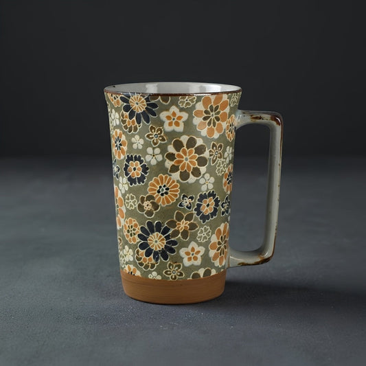 Grand mug Yugen lab en céramique japonaise avec motifs floraux ocre, bleu et crème sur fond vert clair.