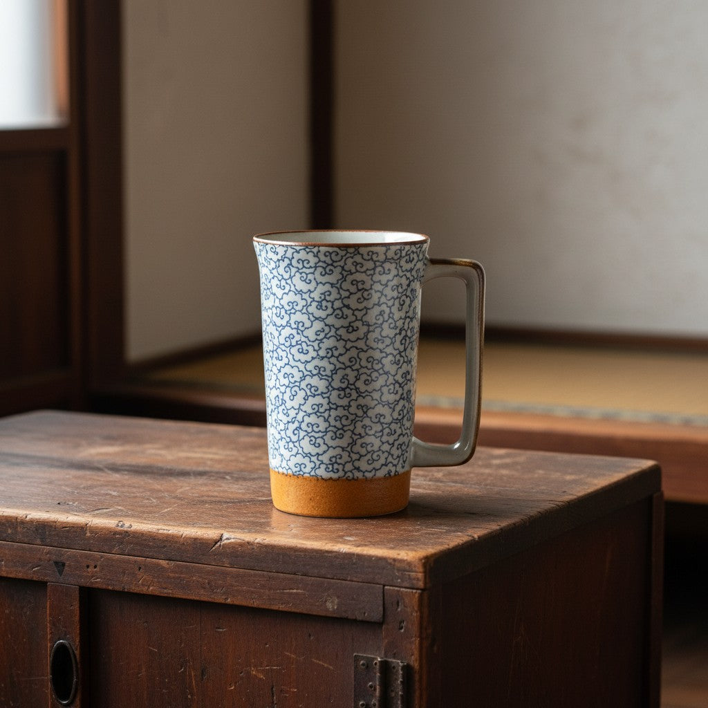Mug japonais Yugen lab en céramique avec motif de nuages bleus sur fond blanc posé sur un meuble en bois ancien