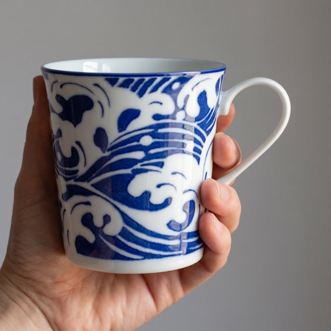 Mug Yugen lab en céramique blanche avec motif de vagues bleu profond tenu en main