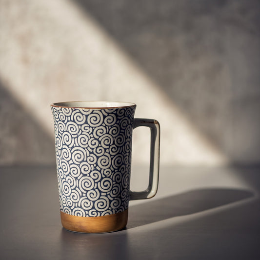Jumbo mug Yugen lab en porcelaine avec motif de spirales bleu profond, base brun doré et anse angulaire.