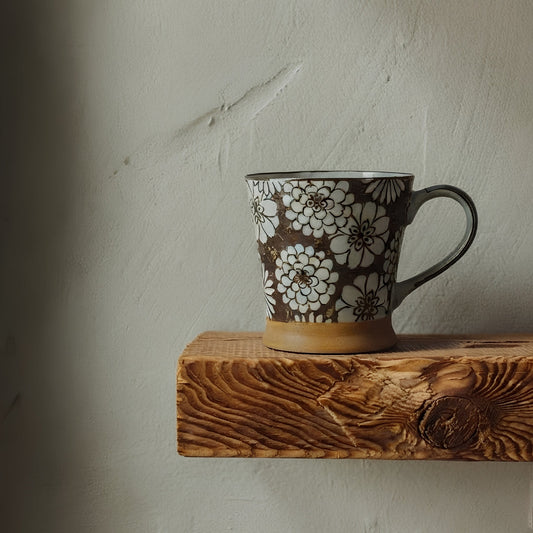 Mug S en porcelaine japonaise Yugen lab avec motifs de fleurs blanches sur fond marron posé sur une étagère en bois