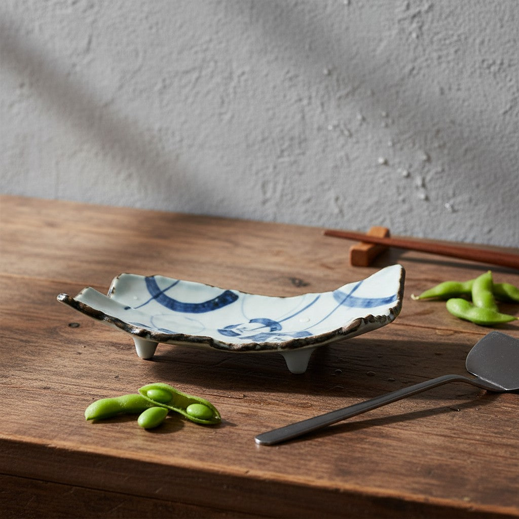 Plat rectangulaire Yugen lab en céramique japonaise avec motif bleu et quatre pieds sur une table en bois